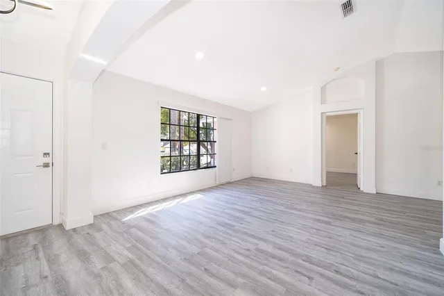 an empty room with wooden floor and windows