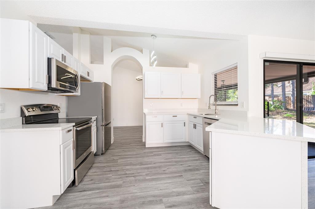 2006 Key Lime Street Ocoee, FL 34761 - Photo 8 of 28 a kitchen with stainless steel appliances a refrigerator a stove top oven a sink dishwasher and white cabinets with wooden floor