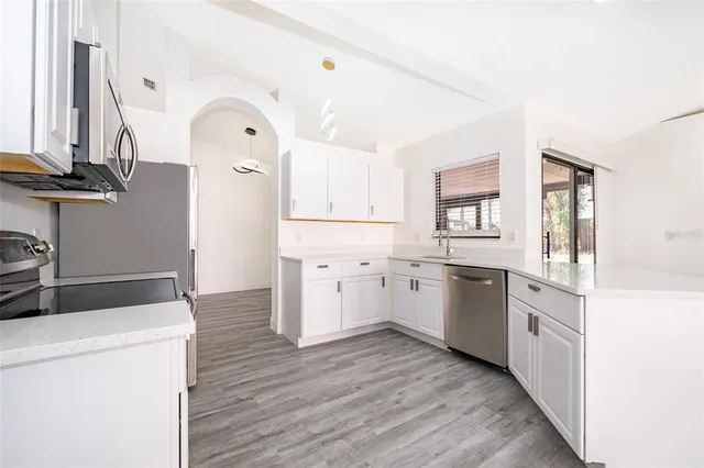 a kitchen with a stove a refrigerator and white cabinets