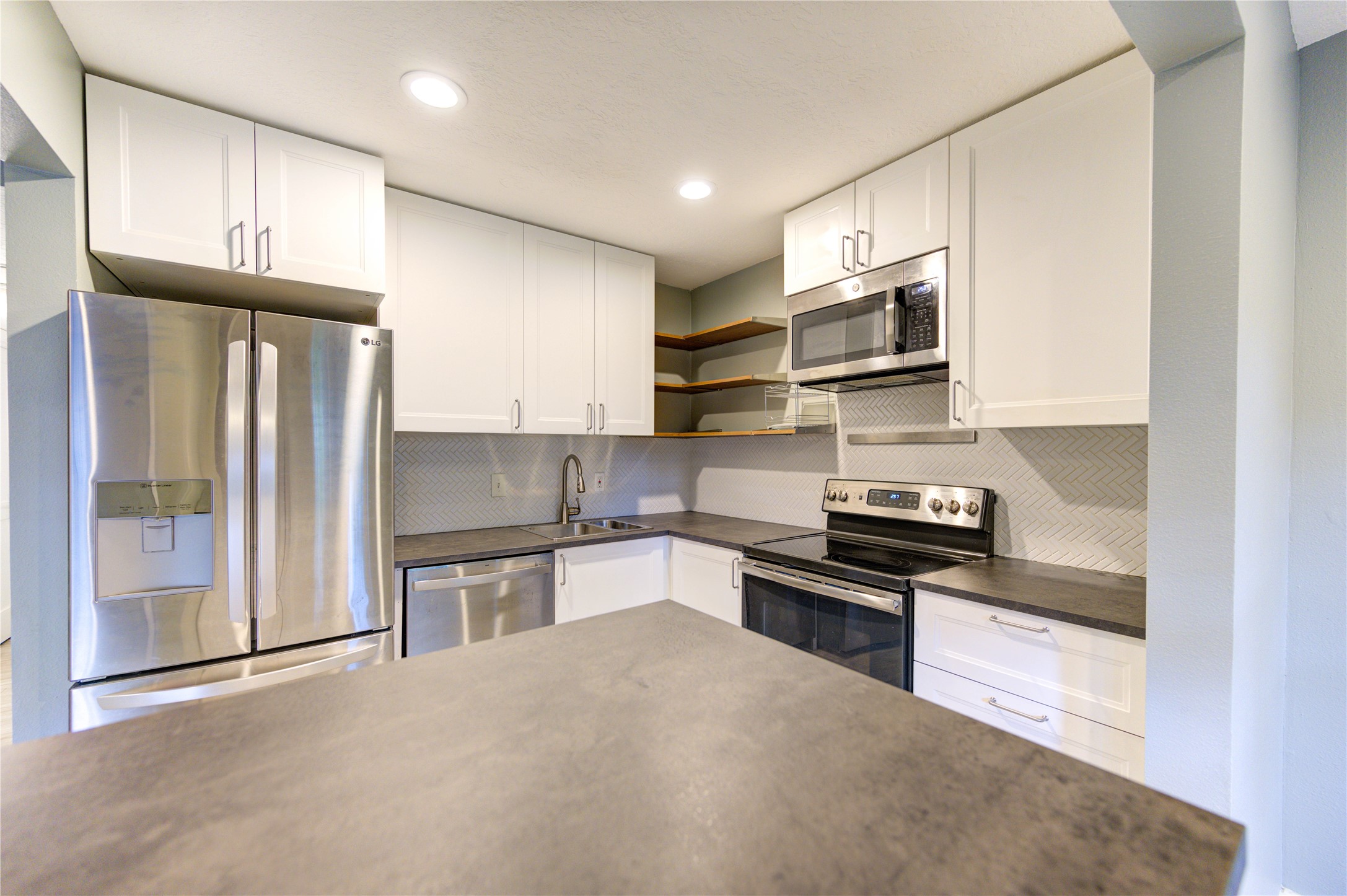 3224 Timmons Lane, Unit 155 Houston, TX 77027 - Photo 18 of 50 a kitchen with stainless steel appliances granite countertop a refrigerator stove microwave and sink