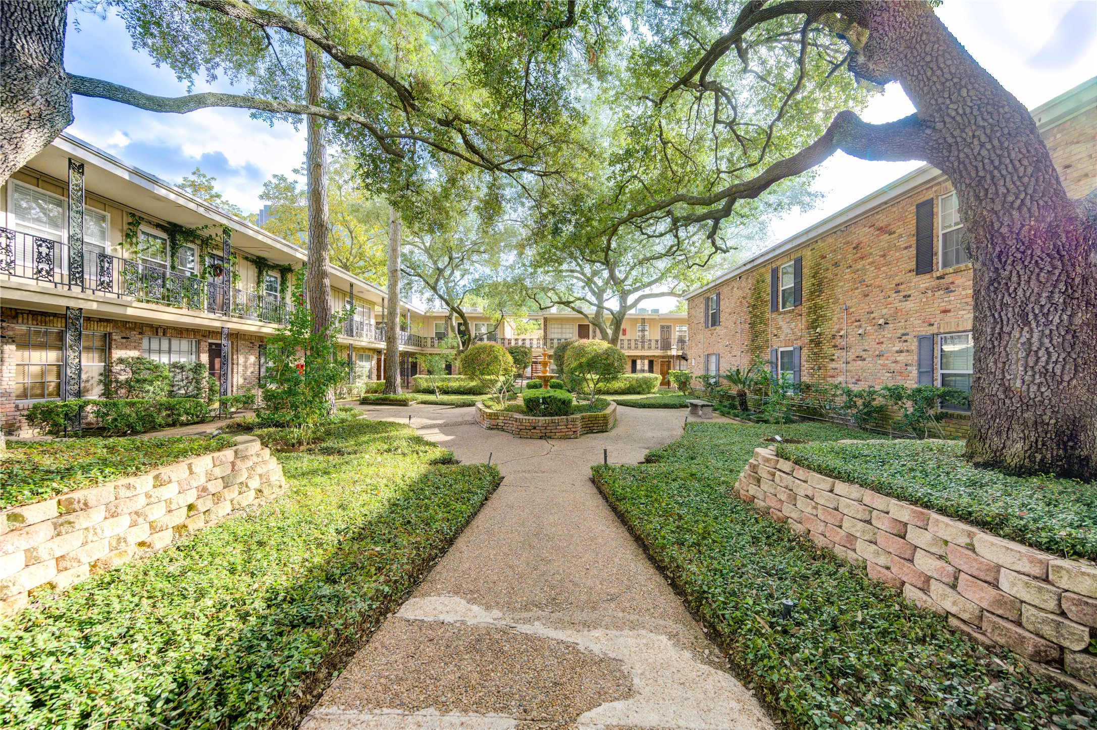 3224 Timmons Lane, Unit 155 Houston, TX 77027 - Photo 36 of 50 a view of a brick house with a yard and table and chairs under an umbrella