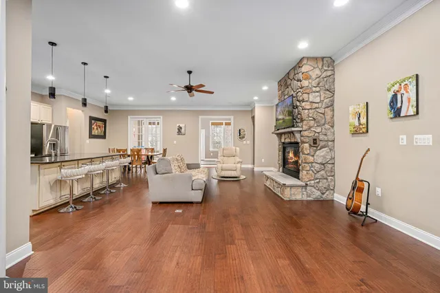 a large kitchen with kitchen island granite countertop a stove a sink a dining table and chairs with wooden floor