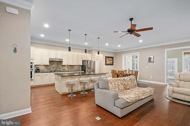 a kitchen with a refrigerator a stove a sink and a dining table with wooden floor