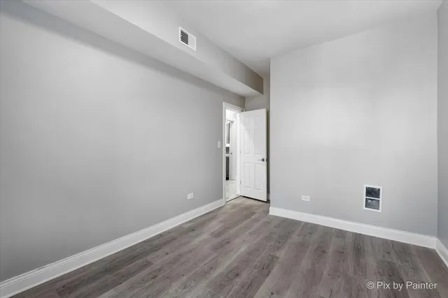 a view of a refrigerator in kitchen and an empty room in wooden floor