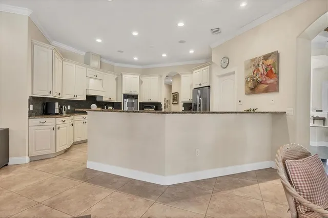 a view of kitchen with stainless steel appliances granite countertop a stove a sink a refrigerator and white cabinets