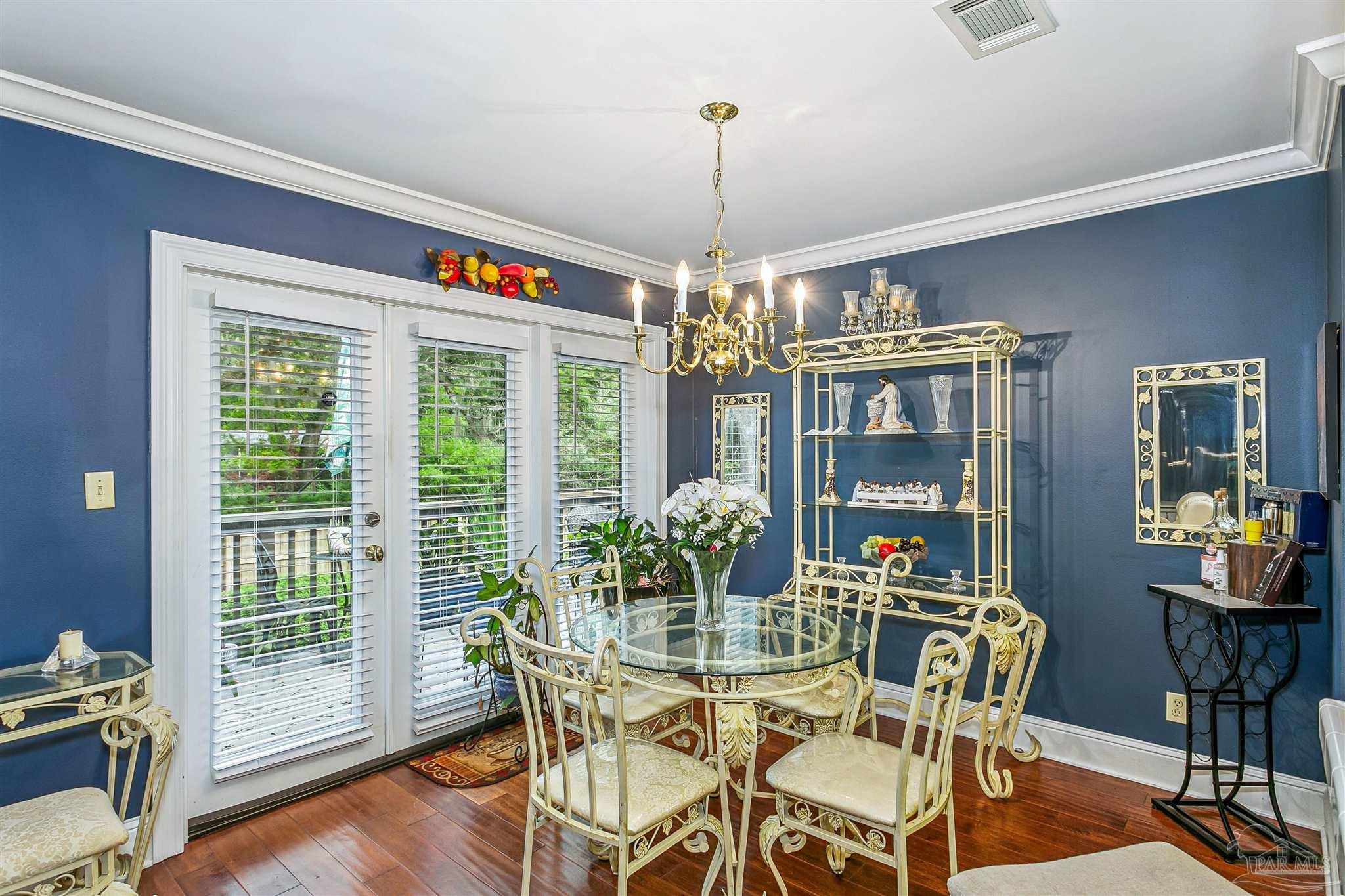 4831 East Olive Road, Unit 2D Pensacola, FL 32514 - Photo 13 of 29 a dining room with furniture a chandelier and wooden floor