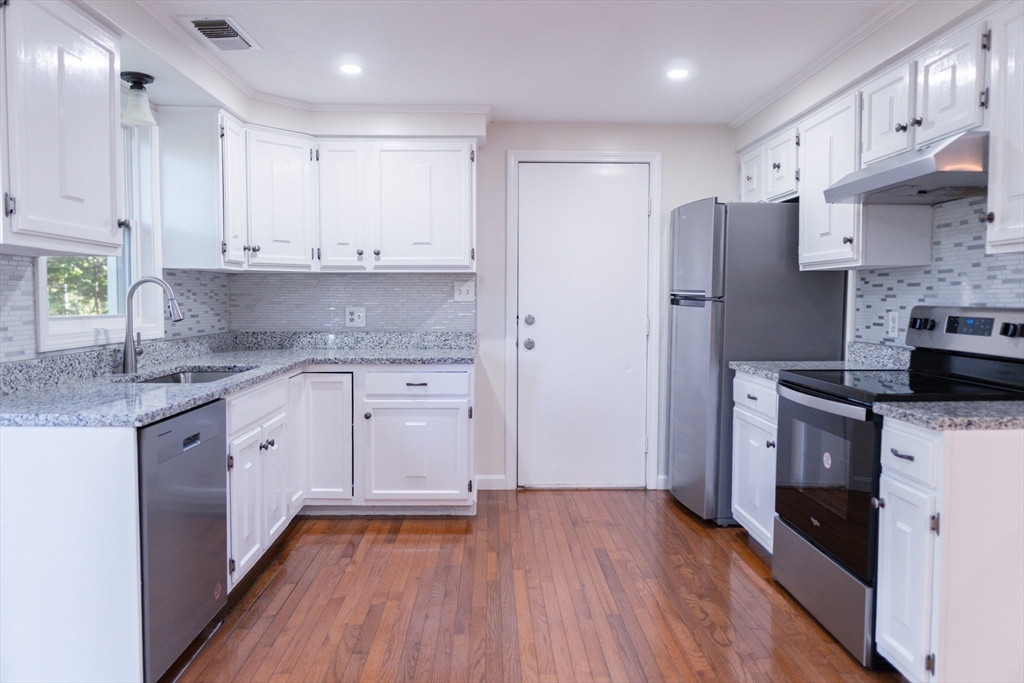 24 Little John Road Falmouth, MA 02536 - Photo 4 of 34 a kitchen with stainless steel appliances granite countertop a refrigerator a sink dishwasher and white cabinets with wooden floor