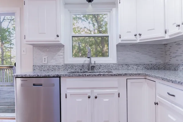 a kitchen with granite countertop white cabinets and a window