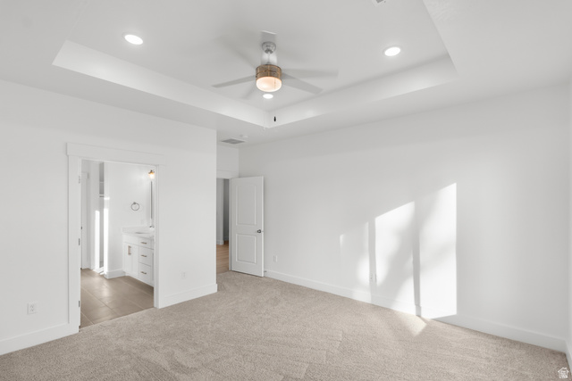 537 South Rivergate Drive Logan, UT 84321 - Photo 11 of 20 Spacious room featuring a tray ceiling with recessed lighting, a ceiling fan, plush carpet flooring, and a doorway opening to a bathroom with a white vanity and tile flooring