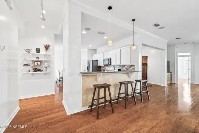 a kitchen with stainless steel appliances granite countertop a table chairs refrigerator and sink