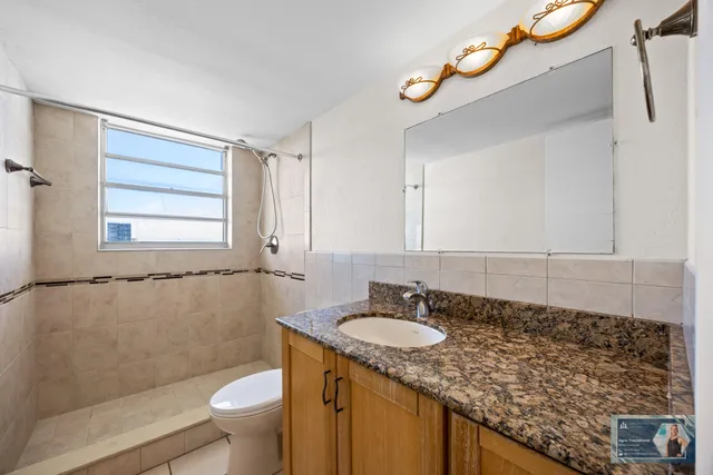 a bathroom with a granite countertop sink toilet and shower