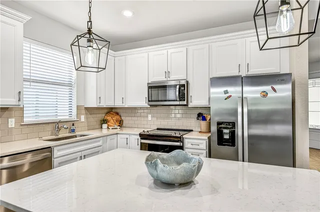 a kitchen with stainless steel appliances a stove a sink a refrigerator and cabinets