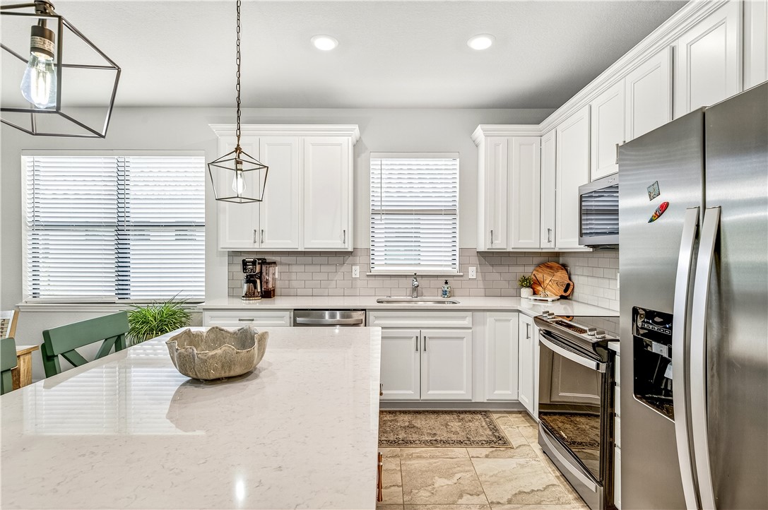 4229 Silver Maple Way Vero Beach, FL 32967 - Photo 9 of 36 a kitchen with stainless steel appliances granite countertop a sink a stove a refrigerator cabinets and a window