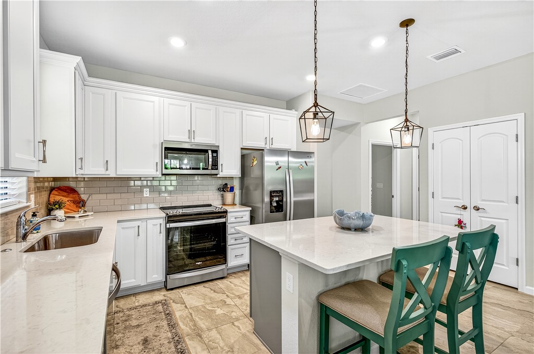 4229 Silver Maple Way Vero Beach, FL 32967 - Photo 10 of 36 a kitchen with kitchen island a stove a table and chairs