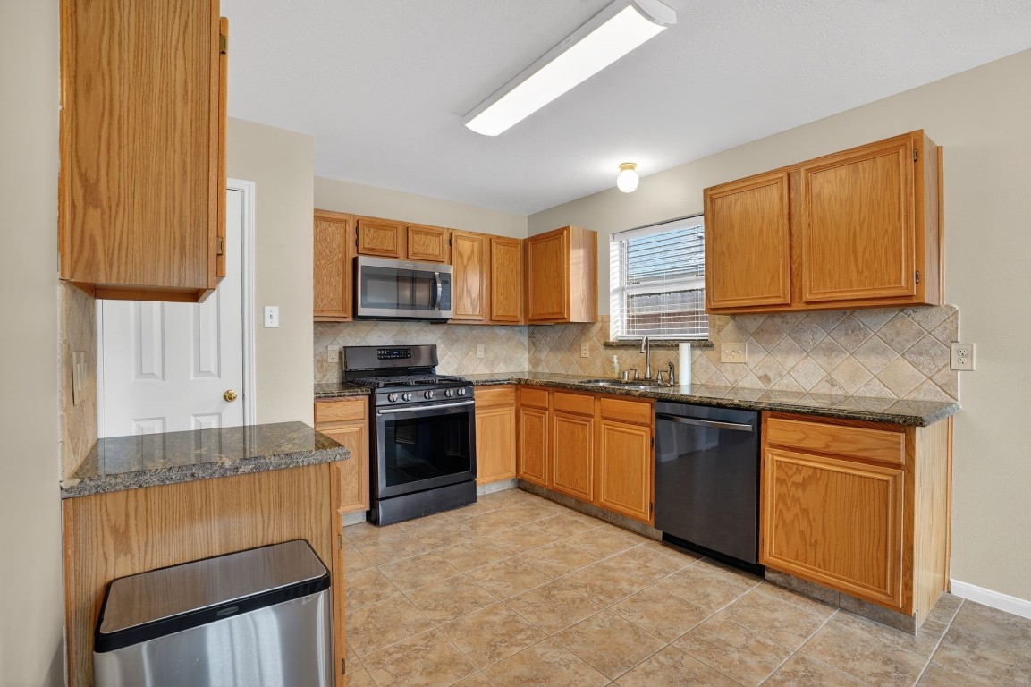 18622 Timbers Drive Humble, TX 77346 - Photo 13 of 34 a kitchen with stainless steel appliances granite countertop wooden cabinets a stove top oven a sink and dishwasher