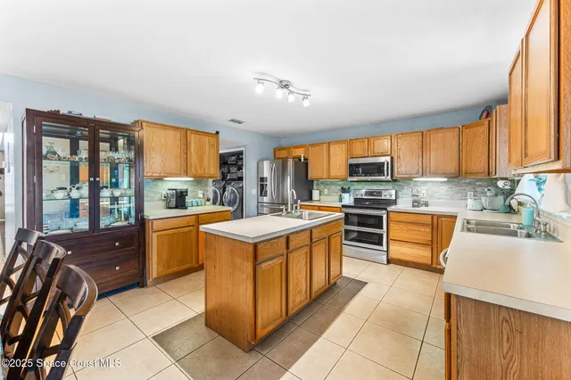 a large kitchen with stainless steel appliances granite countertop a stove top oven a sink a dining table and chairs
