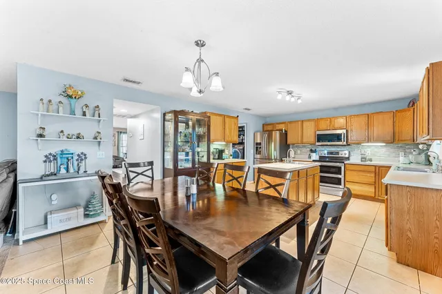 a dining room with stainless steel appliances a table and chairs