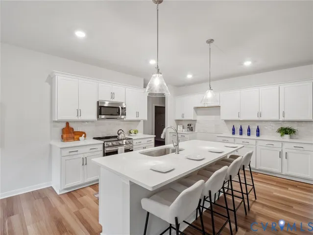 a kitchen with a dining table chairs stove and white cabinets
