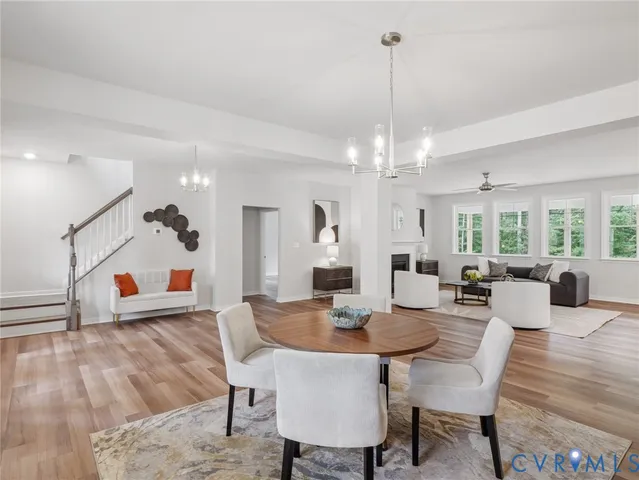 a view of a dining room and livingroom with furniture wooden floor a chandelier and a rug