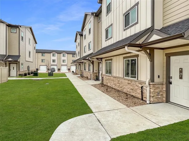 a view of a white house with a yard table and chairs