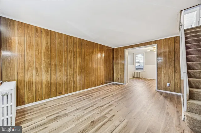 a view of a room with wooden floor and kitchen view