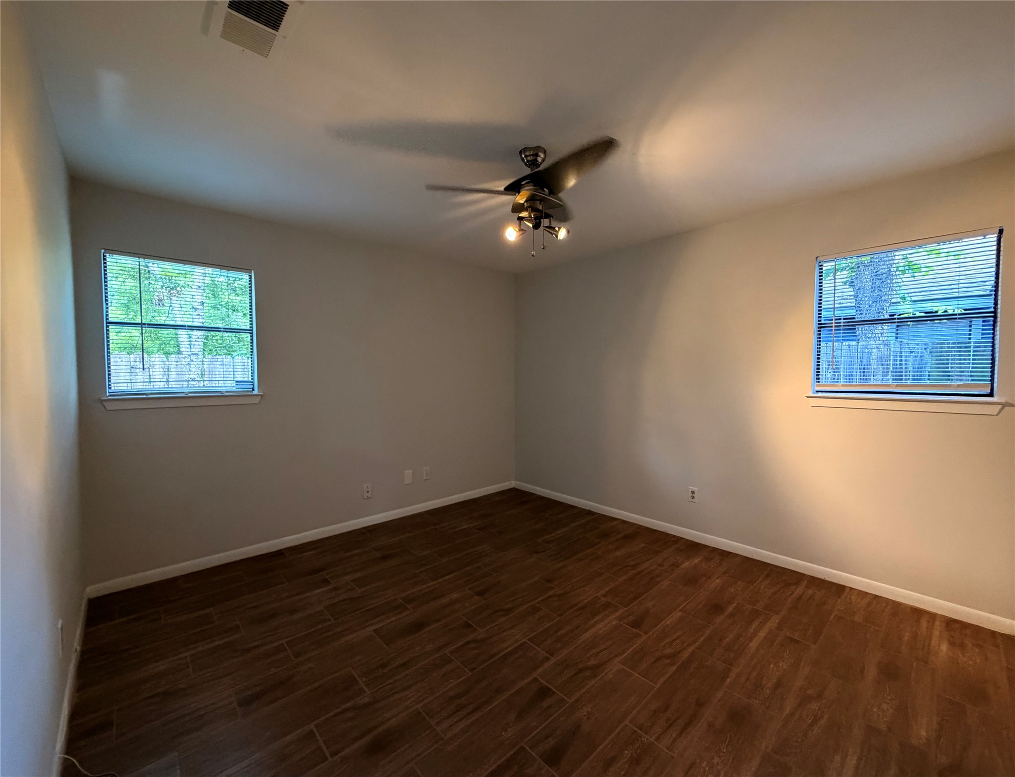 604 Gaylor Street, Unit A Austin, TX 78752 - Photo 4 of 5 Two luminous windows frame a spacious bedroom featuring rich wood-look tile flooring.