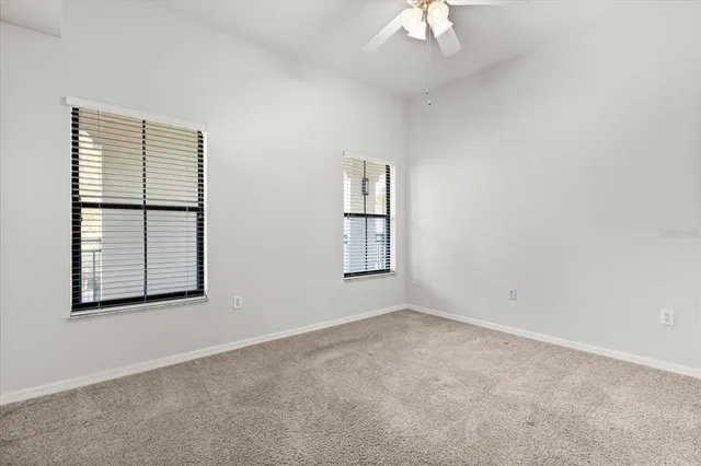 an empty room with windows and chandelier fan