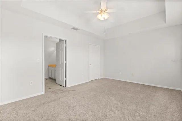 an empty room with a chandelier fan and windows