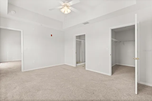 a view of an empty room with a chandelier fan