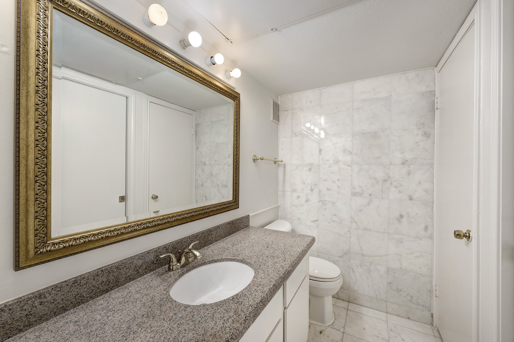 1601 South Shepherd Drive, Unit 224 Houston, TX 77019 - Photo 11 of 14 a bathroom with a granite countertop sink a mirror and a toilet
