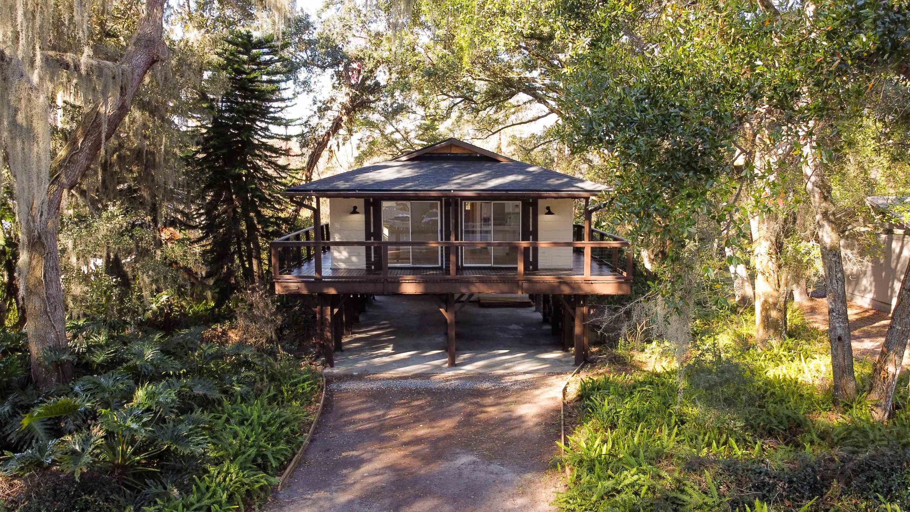 114 Cardinal Road St. Augustine, FL 32086 - Photo 25 of 30 a view of a patio with table and chairs under an umbrella with large trees