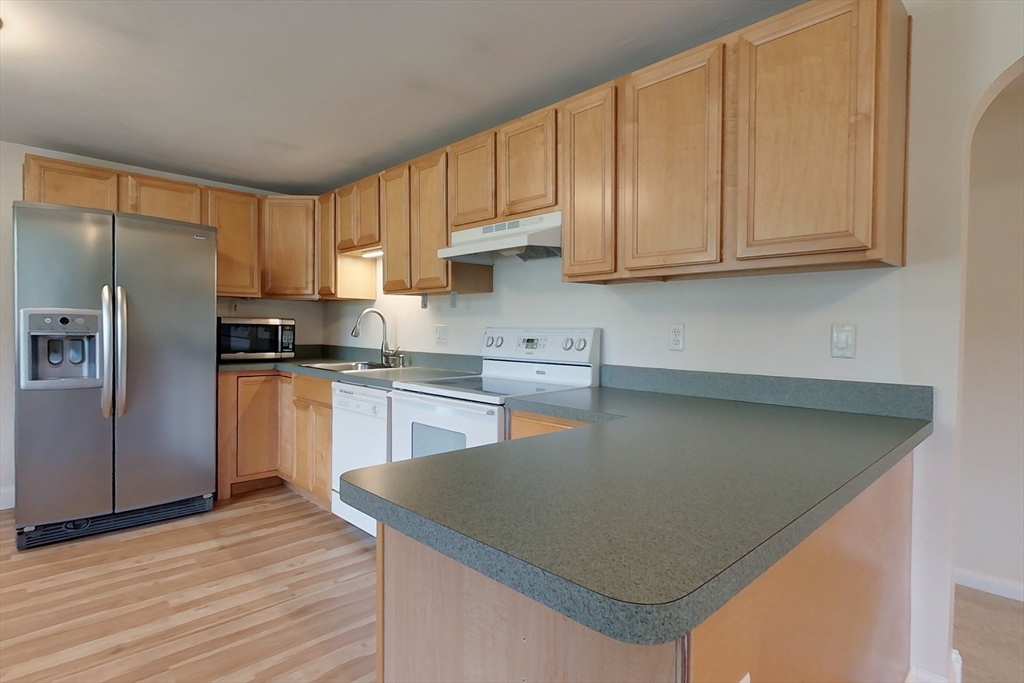 103 Lowell Road Pepperell, MA 01463 - Photo 3 of 42 a kitchen with stainless steel appliances granite countertop a refrigerator a sink dishwasher a stove and white countertops with wooden floor