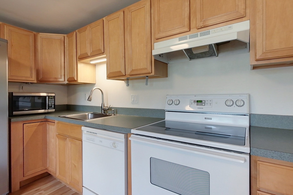 103 Lowell Road Pepperell, MA 01463 - Photo 4 of 42 a kitchen with stainless steel appliances granite countertop a sink a stove and white cabinets
