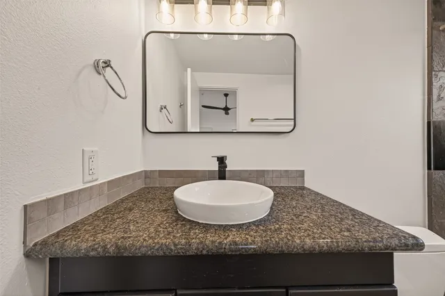 a bathroom with a granite countertop sink and a toilet