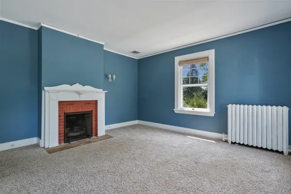 a view of an empty room with window and fire place