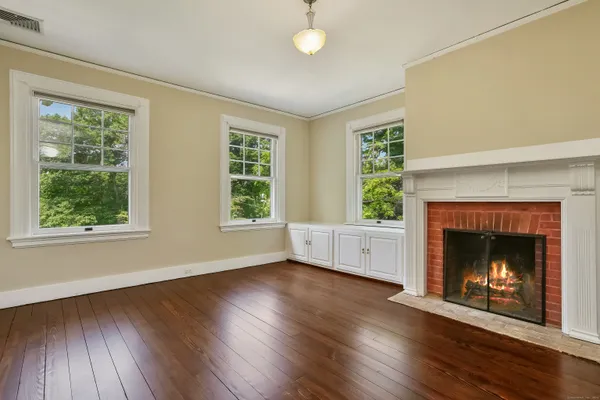 a view of an empty room with wooden floor fireplace and a window