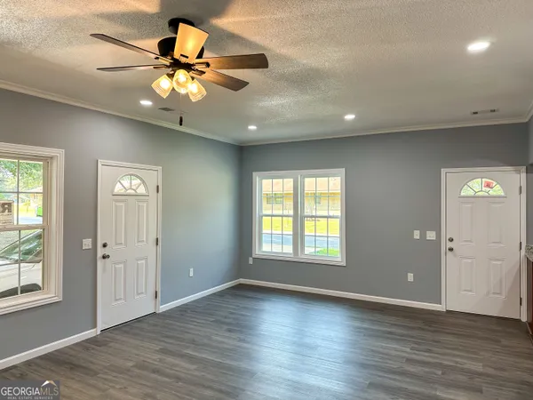 an empty room with wooden floor fan and windows