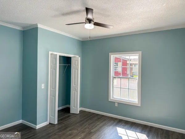 an empty room with wooden floor chandelier fan and windows