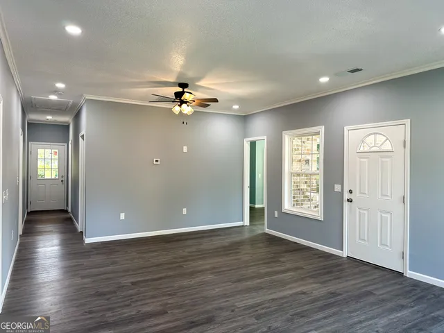 an empty room with wooden floor and windows