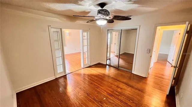 a view of an empty room with wooden floor and a window