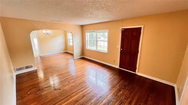 a view of an empty room with window and wooden floor