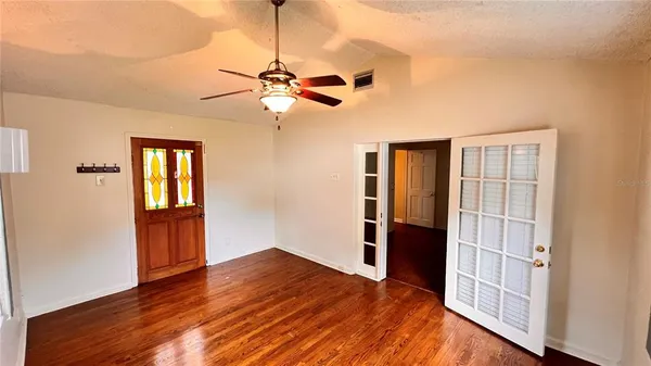a view of empty room with wooden floor and fan