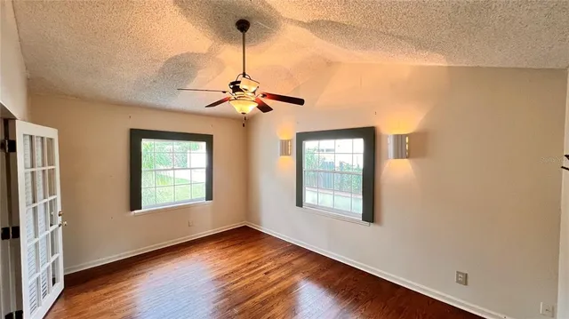 a view of empty room with wooden floor and fan