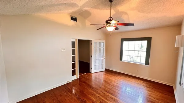 a view of a room with wooden floor ceiling fan and window