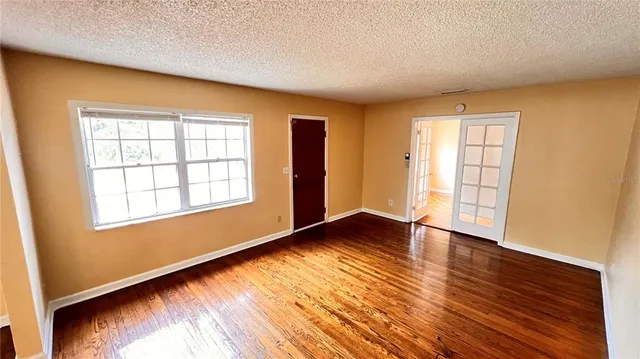 an empty room with wooden floor and windows