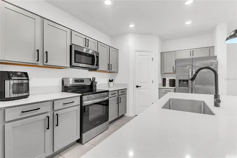 a kitchen with stainless steel appliances granite countertop a sink and stove top oven with white cabinets