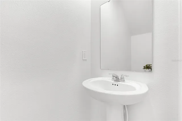 a white sink sitting under a mirror