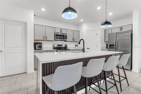 a kitchen with stainless steel appliances granite countertop a dining table chairs refrigerator and cabinets