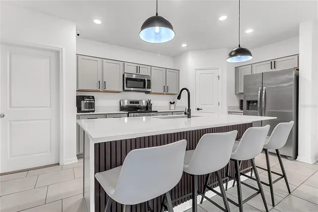 a kitchen with stainless steel appliances granite countertop a dining table chairs refrigerator and cabinets
