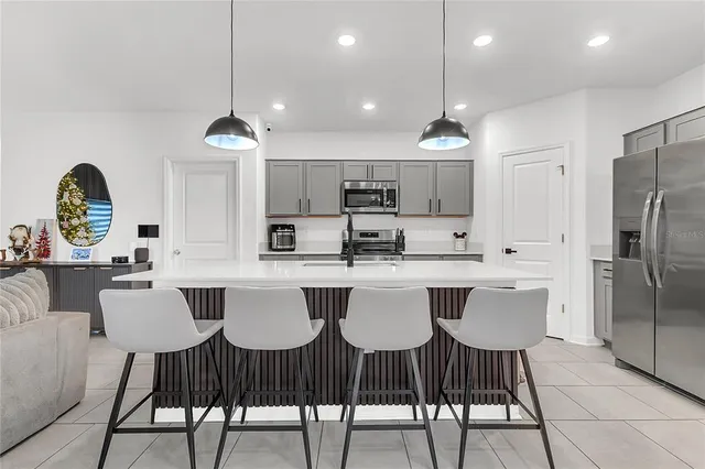 a kitchen with stainless steel appliances granite countertop a dining table chairs and a refrigerator
